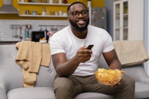 homem vendo tv e comendo salgadinho